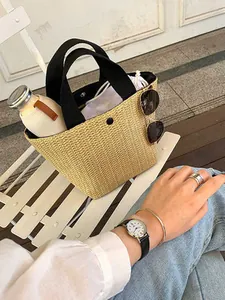 Detail of straw bucket bag featuring black handles and a white drawstring inner pouch