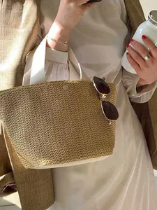Minimalist straw woven tote bag with fabric handles and metallic snap button for summer beach