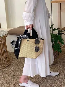 Woven straw tote bag with black handles and geometric scarf for beach vacations