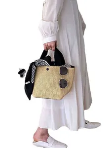 Handwoven straw tote bag with black handles and polka dot scarf decoration