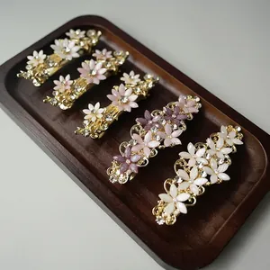 Detail of five vintage gold hair clips with floral rhinestones on a wooden tray