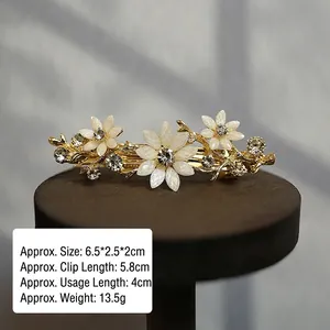 Detail view of flower hair clip with white petals and rhinestones measuring 6.5x2.5 cm