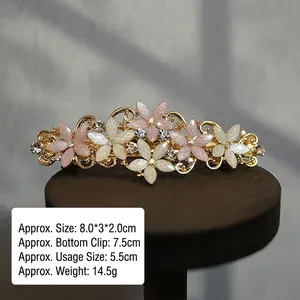 Detailed view of vintage flower hair clip with pink pearls and rhinestones on wooden stand