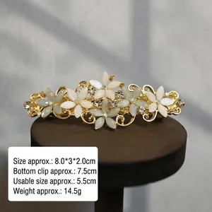 Detail of floral hair clip with light petals and rhinestones on golden alloy base