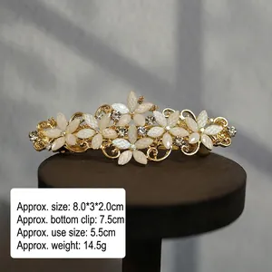 Close-up of elegant gold flower hair clip with white pearls and sparkling rhinestones
