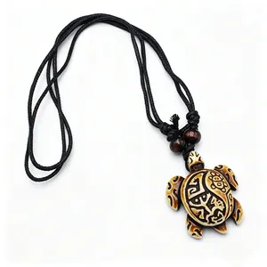 Détail du pendentif tortue tribale avec gravures sur cordon noir et perles en bois