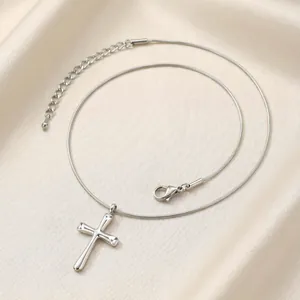 Vue détaillée du pendentif croix en argent poli avec chaîne serpent réglable sur de la soie