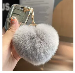 Gros plan du porte-clés cœur en peluche gris clair avec fourrure douce et fermoir doré
