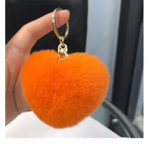 Gros plan du porte-clés cœur en fausse fourrure orange avec anneau doré et mousqueton