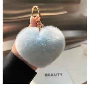 Gros plan du porte-clés cœur en fausse fourrure bleu clair avec anneau doré poli