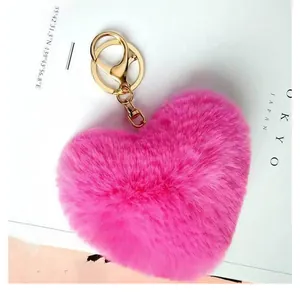 Détail d'un porte-clés en peluche douce en forme de cœur rose avec fermoir en métal doré