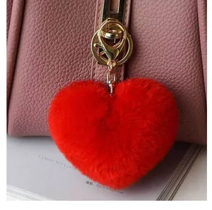 Gros plan d'un porte-clés cœur rouge en peluche avec fermoir doré sur un sac à main rose