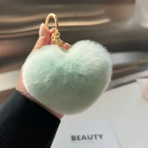 Porte-clés cœur en peluche vert menthe avec anneau doré tenu à la main pour décoration