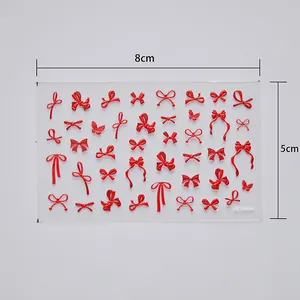Detailed view of 3D red bow and butterfly nail art stickers on a 8x5cm transparent sheet