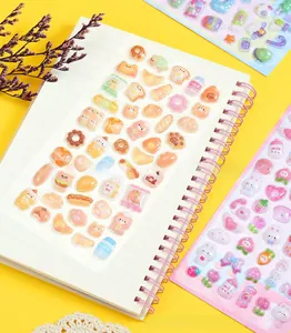 Detailed close-up of 3D embossed cartoon stickers on a white notebook with bright props
