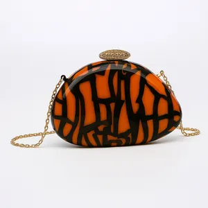 Detailed view of orange and black acrylic clutch with crystal-encrusted gold clasp