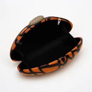 Inside view of an orange and black acrylic shell clutch bag with gold crystal metal clasp