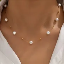 Detail of elegant pearl necklace with gold beads on model wearing white shirt