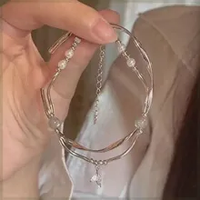 Detail of silver layered bracelet featuring a fishtail pendant and white pearls
