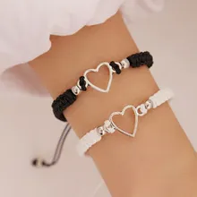 Close-up of woven couple bracelets with hollow heart charms in black and white cords