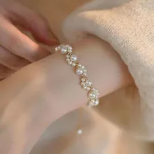 Detailed view of elegant multi-size pearl bracelet with gold adjustable chain on wrist