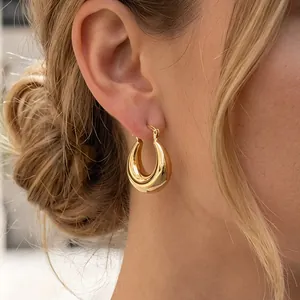 Polished chunky gold hoop earrings with minimalist textured design on female model