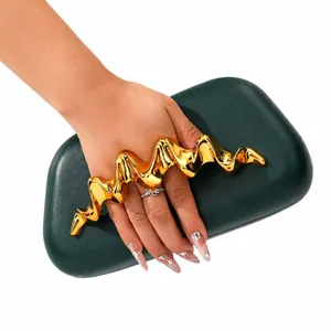 Détail d'une pochette vert foncé en PU avec poignée design en métal doré ondulé