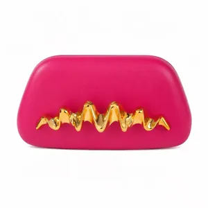 Détail de la poignée en métal doré ondulé sur la pochette en cuir lisse rose vif