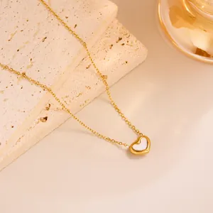 Detail shot of heart-shaped white shell pendant on a gold titanium steel necklace