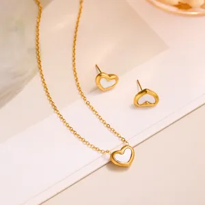 Detail view of gold titanium necklace and heart stud earrings with white shell inlay