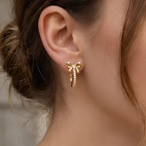 Elegant 18K gold-plated bow earrings with sparkling cubic zirconia on a female model