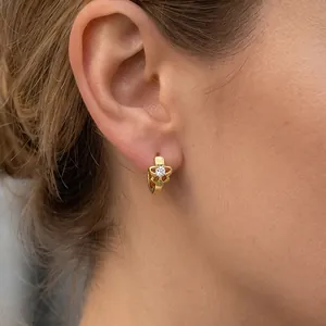 Close-up of elegant gold hollow flower earrings with zircon on a model's ear