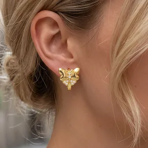 Detailed view of an 18K gold-plated bow butterfly earring with cubic zirconia on a model