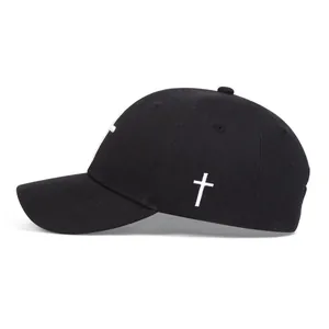 Detail view of white cross embroidery on black cotton canvas baseball cap side