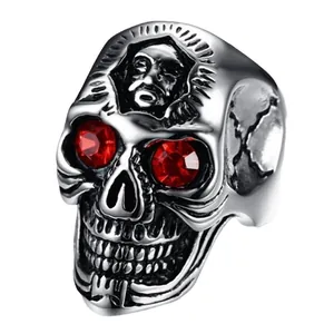 Punk style skull ring with red gemstone eyes and religious relief on silver band