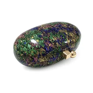Detailed macro view of acrylic shell evening bag with colorful stone textures and gold clasp