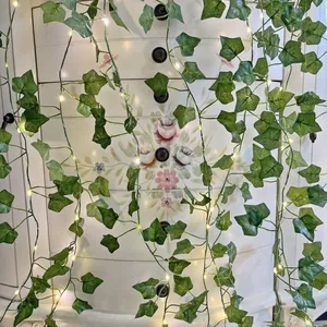 Macro detail of artificial ivy vine with warm white LED string lights for garden decor