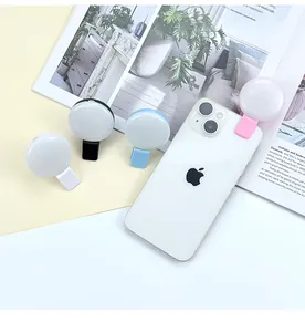 Close-up of a mini clip-on LED selfie ring light in pink attached to a smartphone