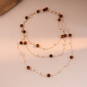 Detail of layered gold necklace with brown tiger eye beads and white pearls