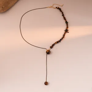 Detail of asymmetrical tiger eye beaded necklace with black cord and gold clasp