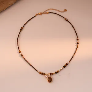 Detail of tiger eye beaded necklace with gold rimmed pendant and zircon charms