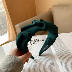 Pleated wide-brimmed headband in dark green fabric with handmade label detail