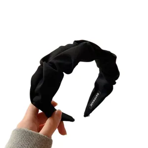 Minimalist black pleated fabric wide headband featuring a handmade inner label detail