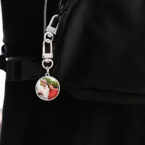 Sublimation round photo keychain with silver swivel hook attached to a black fabric backpack