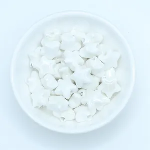 Macro shot of white glazed ceramic star beads for handmade jewelry in a white bowl