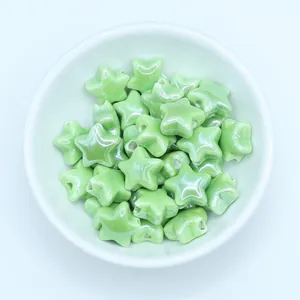 Close-up of grass green glazed ceramic star beads for DIY jewelry making in a white bowl
