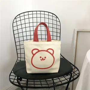 Minimalist cream canvas lunch tote with red cartoon bear pattern and durable red handles