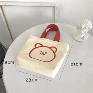 Detailed dimensions of off-white canvas lunch bag with red bear print and handles
