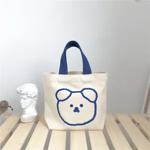 Close-up of canvas lunch bag with cute bear print on a light wooden background
