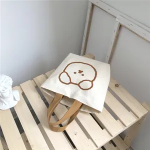 Detailed close-up of a cream canvas lunch bag with a cute brown cartoon bear print